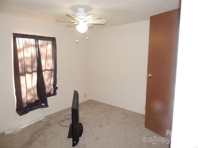 workout area featuring a textured ceiling, light carpet, and ceiling fan