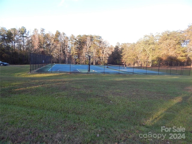 view of tennis court with a lawn and basketball hoop