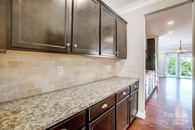 kitchen featuring dark brown cabinetry, decorative light fixtures, dark hardwood / wood-style floors, and crown molding