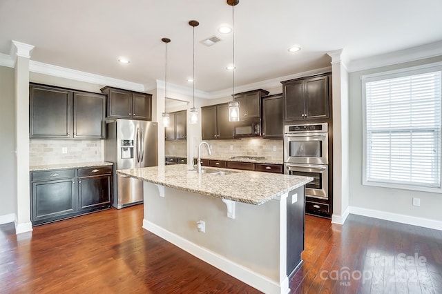 kitchen featuring stainless steel appliances, sink, hanging light fixtures, a kitchen island with sink, and dark hardwood / wood-style flooring