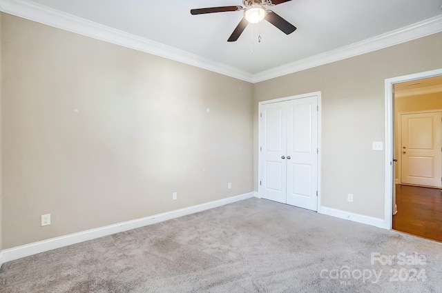 unfurnished bedroom featuring carpet floors, ceiling fan, crown molding, and a closet