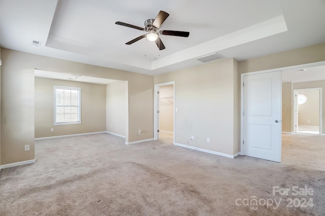 spare room featuring light carpet, ceiling fan, and a tray ceiling