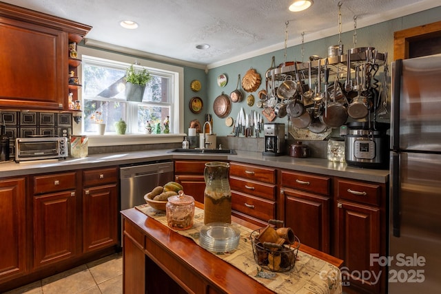 kitchen featuring light tile patterned floors, appliances with stainless steel finishes, a textured ceiling, crown molding, and sink