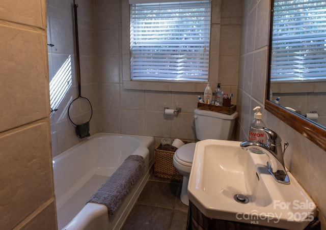 bathroom featuring toilet, sink, tile walls, and tile patterned floors