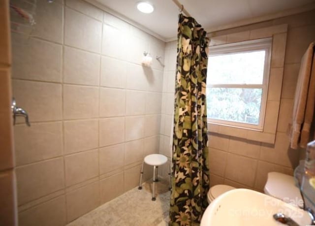 bathroom with toilet, a shower with shower curtain, and tile walls