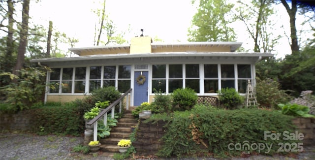 view of front of house featuring a chimney and a sunroom