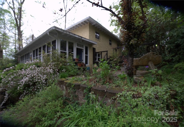 view of side of home featuring a sunroom and stucco siding