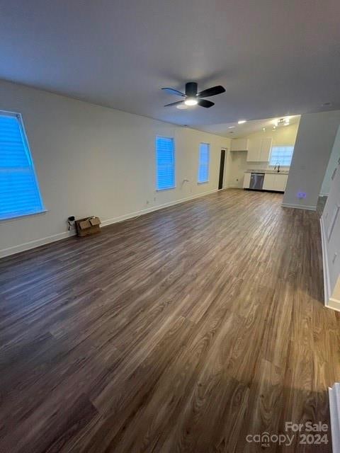 unfurnished living room with dark hardwood / wood-style flooring and ceiling fan