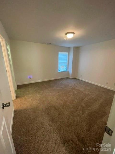 spare room with dark colored carpet