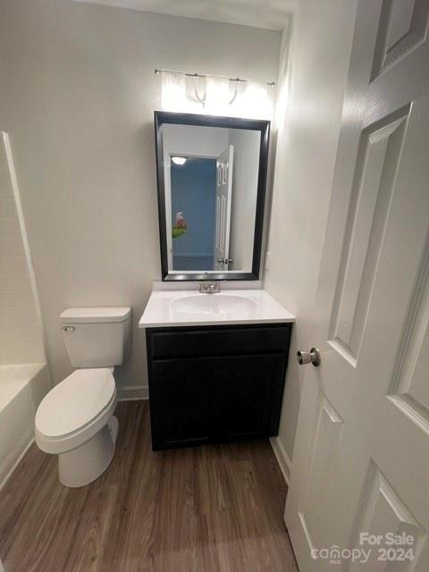 bathroom with toilet, vanity, and hardwood / wood-style flooring