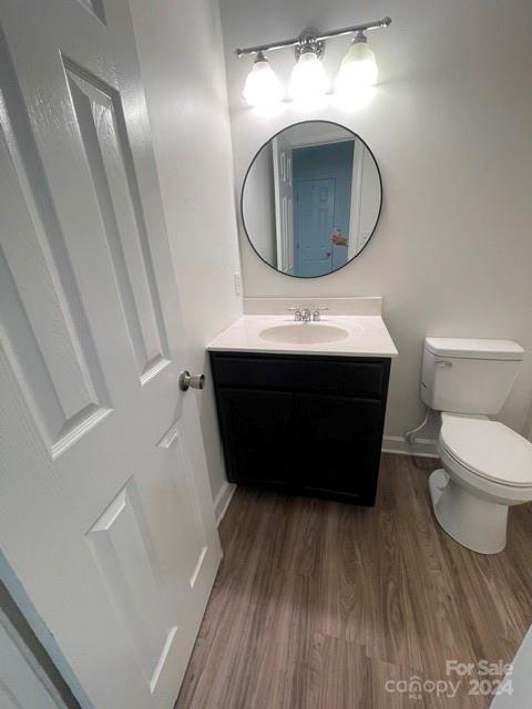 bathroom with toilet, vanity, and hardwood / wood-style flooring