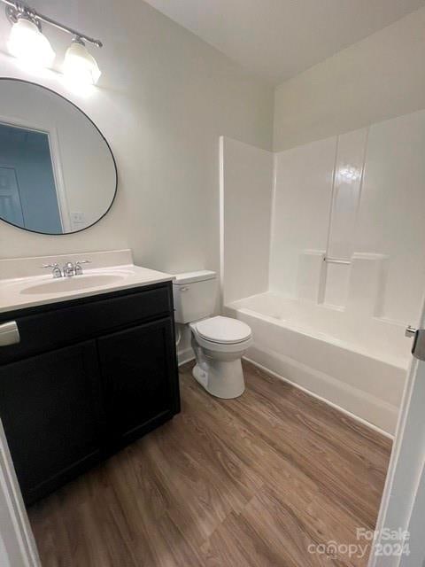 full bathroom with hardwood / wood-style floors, vanity, toilet, and  shower combination