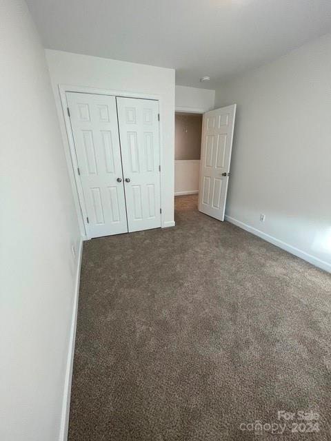 unfurnished bedroom featuring a closet and dark colored carpet