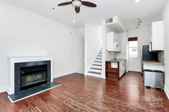 unfurnished living room with ceiling fan, sink, and dark hardwood / wood-style flooring