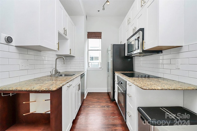 kitchen with white cabinets, appliances with stainless steel finishes, dark hardwood / wood-style floors, and light stone counters