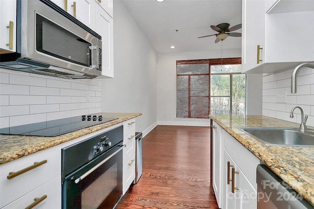 kitchen with appliances with stainless steel finishes, light stone countertops, sink, white cabinets, and dark wood-type flooring