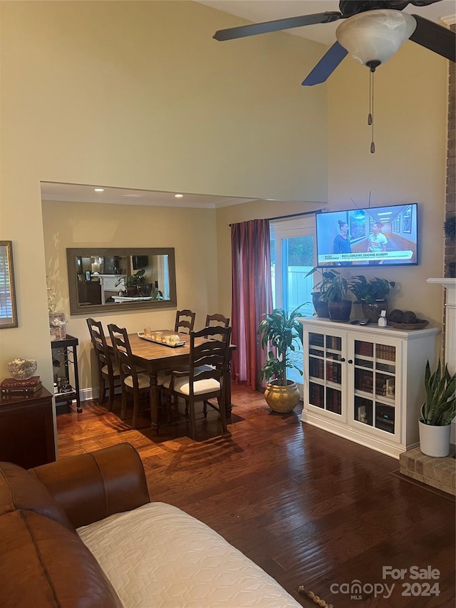 living room featuring hardwood / wood-style flooring, ceiling fan, and a towering ceiling