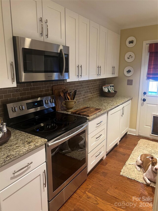 kitchen featuring white cabinets, appliances with stainless steel finishes, wood-type flooring, and light stone counters