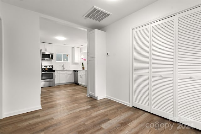 kitchen with white cabinetry, appliances with stainless steel finishes, and hardwood / wood-style flooring