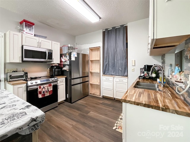 kitchen featuring white cabinetry, sink, stainless steel appliances, wood counters, and a textured ceiling