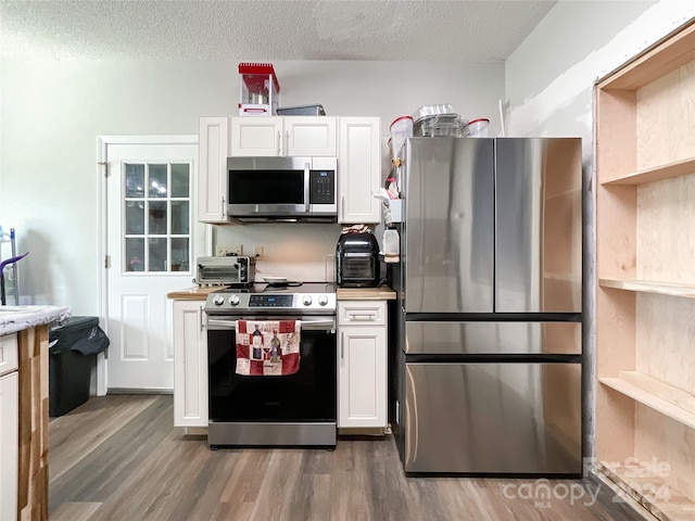 kitchen with white cabinets, a textured ceiling, stainless steel appliances, and hardwood / wood-style flooring