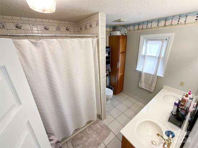 bathroom featuring tile patterned floors, walk in shower, a textured ceiling, vanity, and toilet