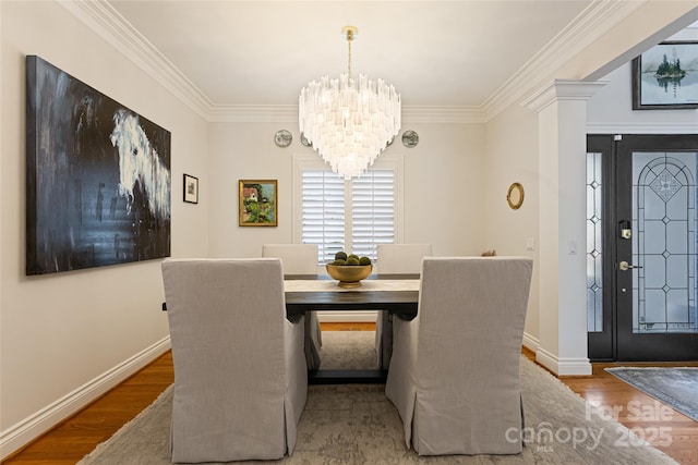 dining room with baseboards, ornamental molding, wood finished floors, and an inviting chandelier