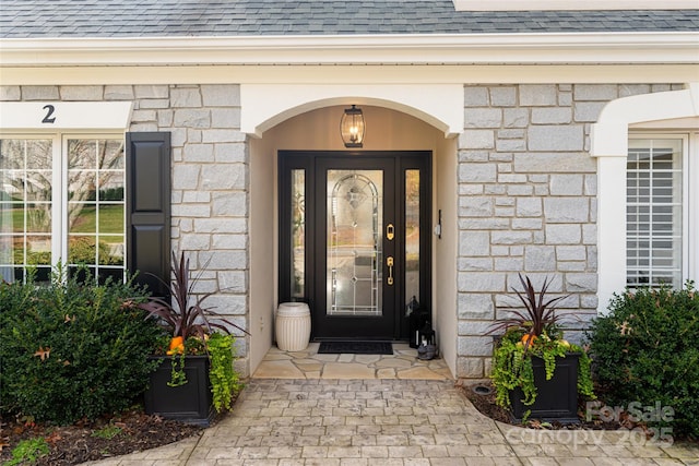 property entrance with stone siding and roof with shingles