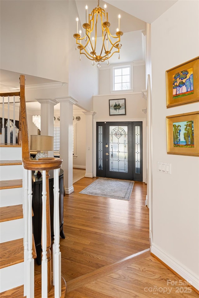 foyer entrance featuring a notable chandelier, a high ceiling, wood finished floors, baseboards, and stairs