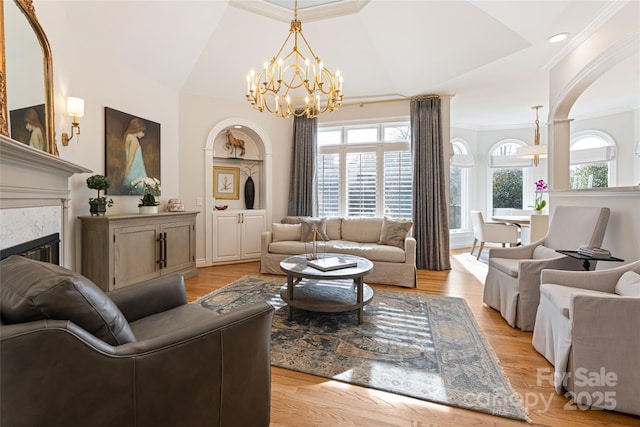 living area featuring a glass covered fireplace, crown molding, and light wood finished floors