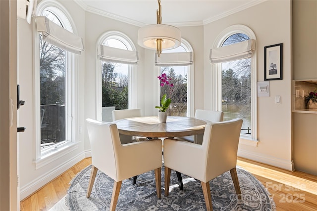 dining space featuring light wood-style floors, crown molding, and baseboards