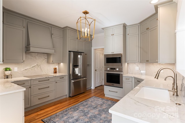 kitchen featuring gray cabinets, custom exhaust hood, stainless steel appliances, and a sink