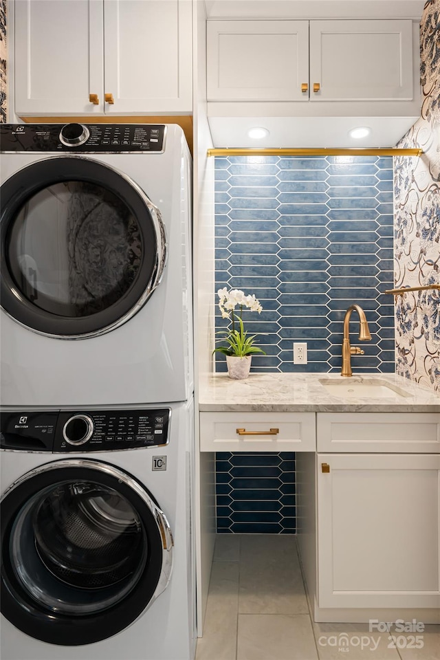 clothes washing area featuring stacked washer / dryer, cabinet space, a sink, and light tile patterned floors