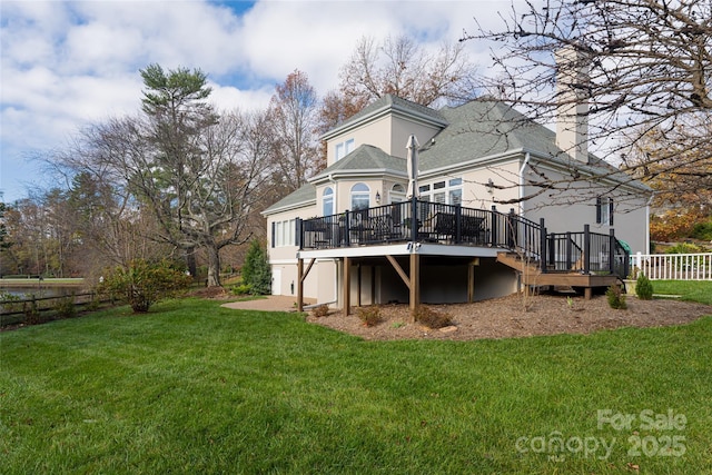 rear view of property featuring a yard, fence, a wooden deck, and stucco siding