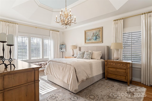 bedroom featuring a raised ceiling, crown molding, and light wood-style flooring