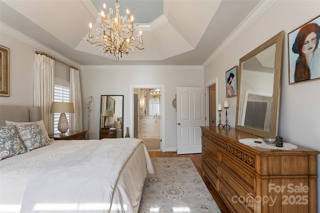 bedroom with ensuite bath, ornamental molding, a raised ceiling, and wood finished floors