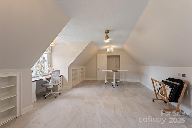 office with built in shelves, visible vents, vaulted ceiling, and a textured ceiling