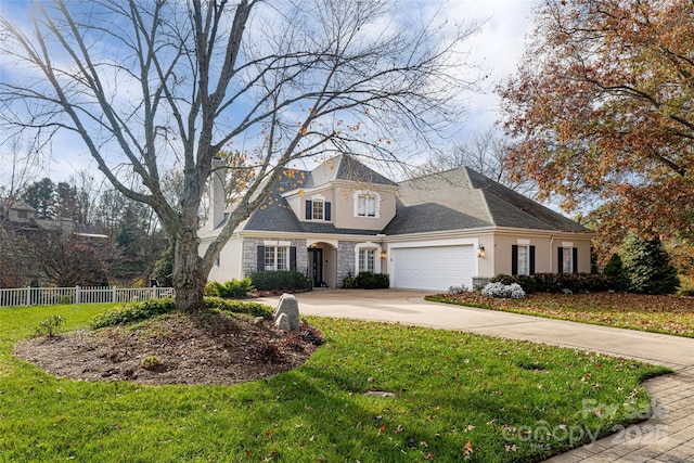 view of front of property featuring an attached garage, driveway, fence, and a front lawn