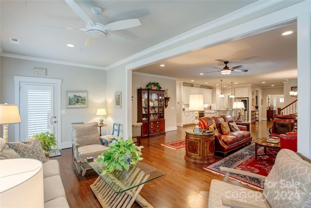 living room featuring hardwood / wood-style flooring, ceiling fan, and ornamental molding