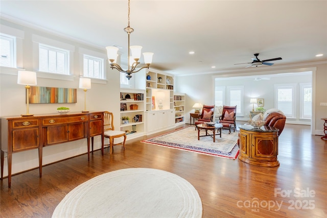 interior space with ceiling fan with notable chandelier, wood finished floors, a wealth of natural light, and crown molding