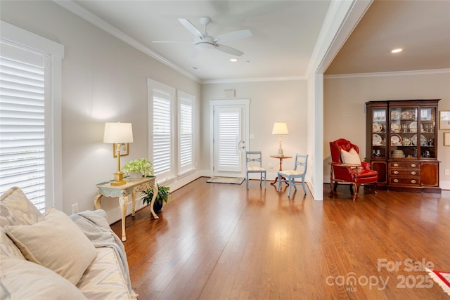 living area with crown molding, baseboards, recessed lighting, wood finished floors, and a ceiling fan