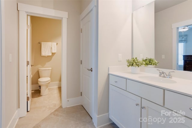 bathroom featuring baseboards, toilet, and vanity