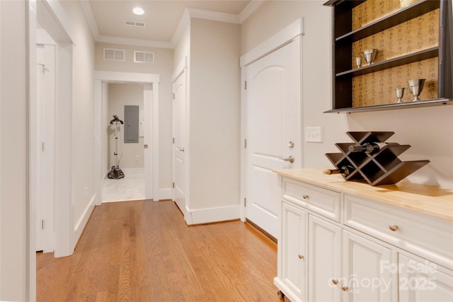 corridor with visible vents, crown molding, electric panel, and light wood finished floors
