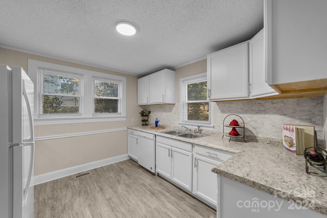 kitchen with white appliances, sink, light wood-type flooring, a textured ceiling, and white cabinetry