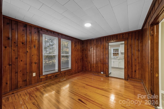 unfurnished room featuring wood walls and light hardwood / wood-style flooring