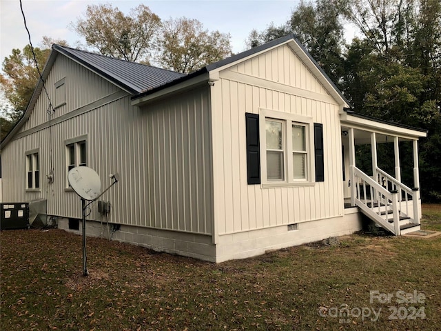 view of side of home with central AC unit and a lawn