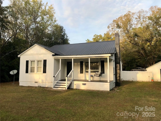 view of front of property featuring metal roof, fence, crawl space, a front lawn, and covered porch