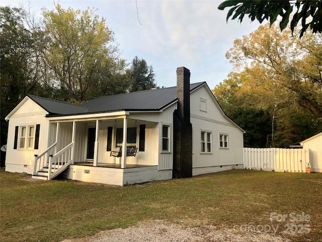 exterior space featuring fence, a chimney, crawl space, a front yard, and a porch