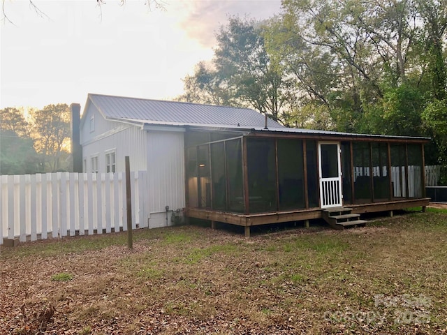 rear view of house with a sunroom, fence, and metal roof