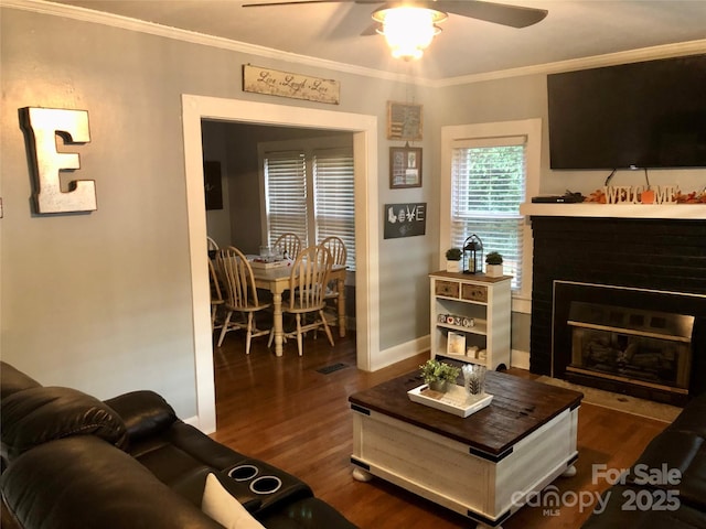 living area featuring dark wood finished floors, a fireplace with flush hearth, and ornamental molding